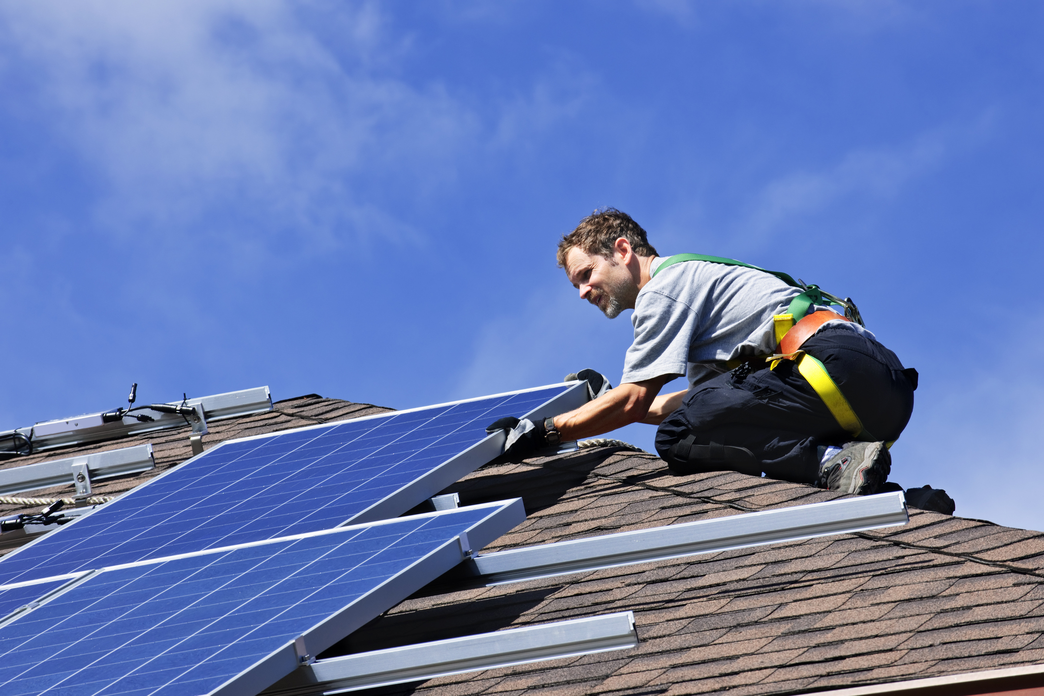 A napelemtelepítést végző szakemberek szereli fel a ház tetejére a paneleket