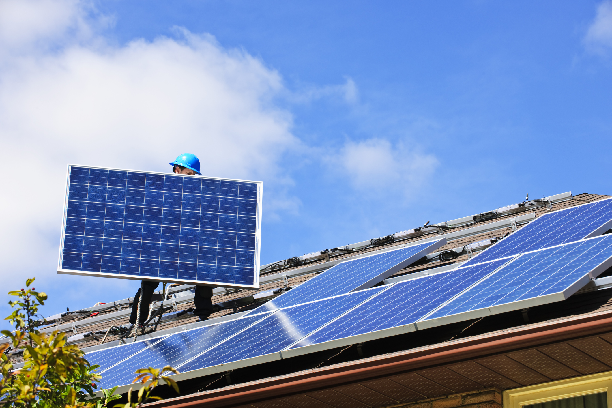 A szakember hordja fel a tetőre a napelem paneleket
